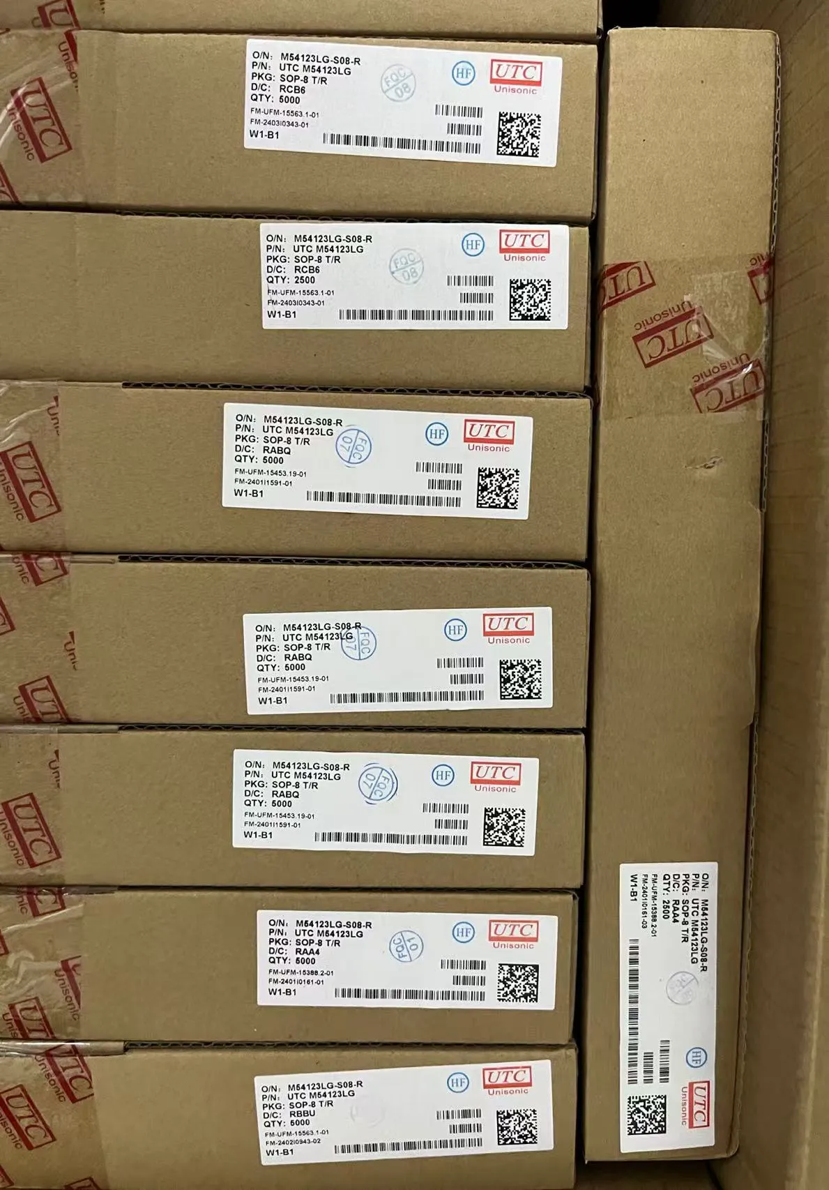 Stacked boxes of UTC Unisonic SOP-8 ICs with visible part numbers, date codes, and quantity labels for incoming inspection